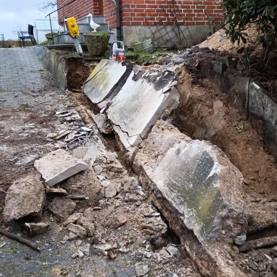 Abbruch einer massiven Betonmauer mit Trennschleifer und aufgebrochenen Betonplatten